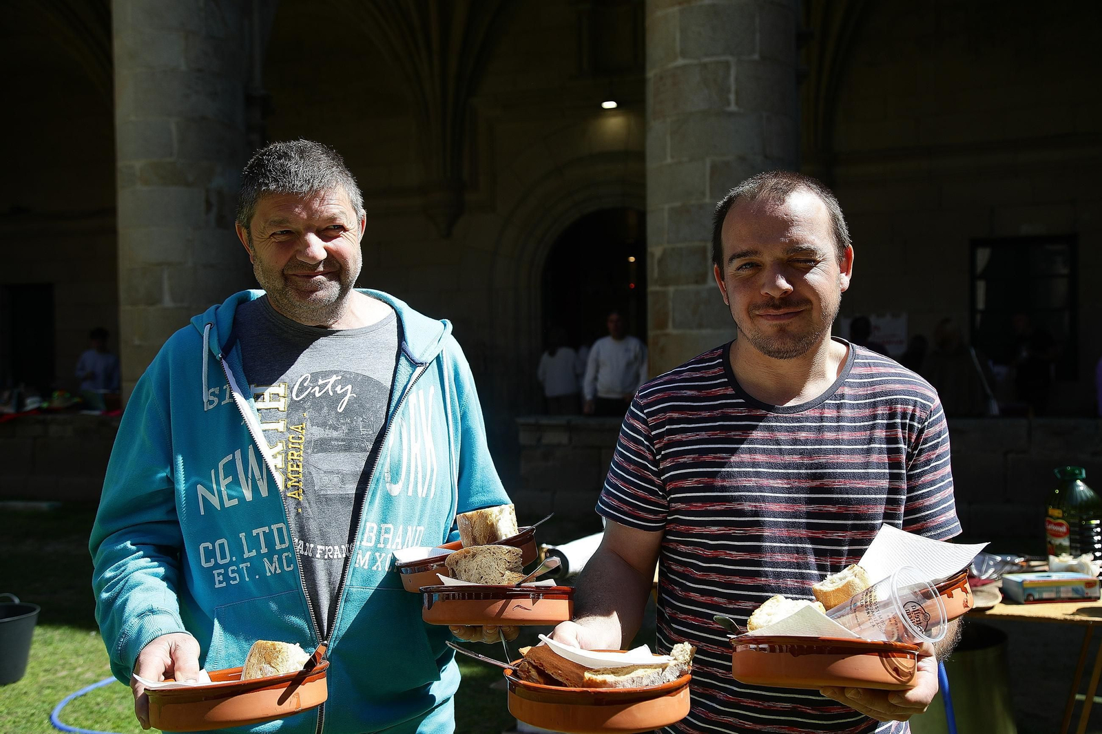 Albino y Carlos cargan varios platos de faba para ser degustados.