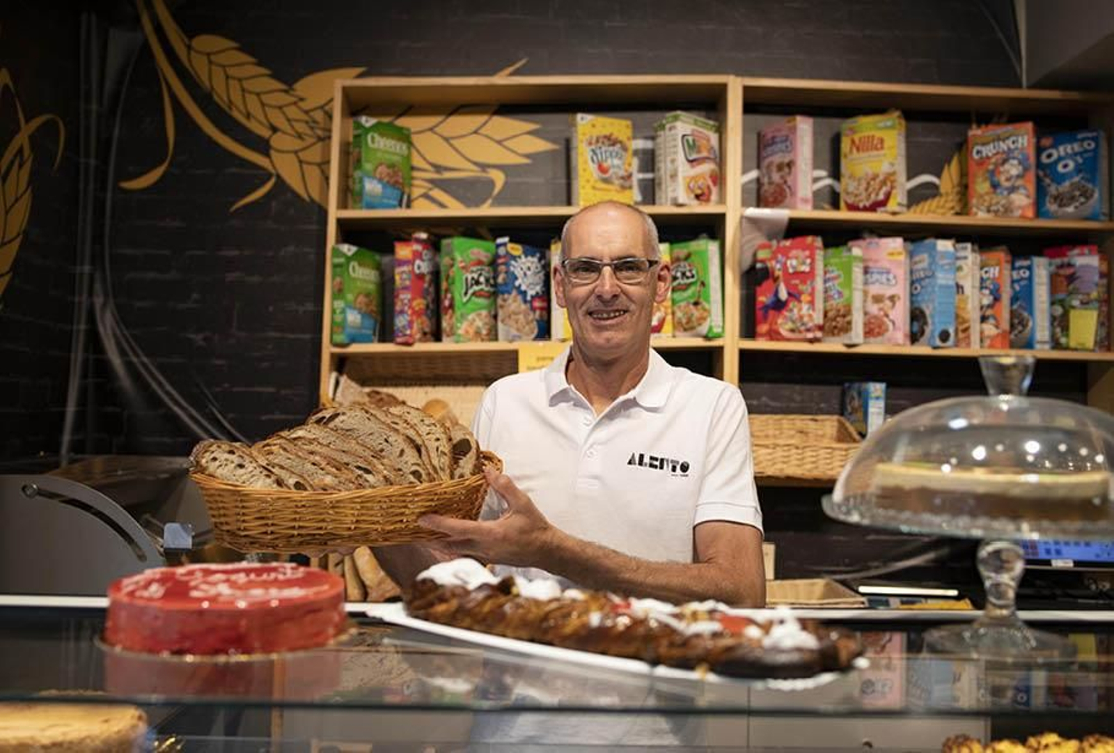 Julio Alén con una cesta de su pan, algunas de sus dulces propuestas y un amplio surtido de cereales de fondo (XESÚS FARIÑAS).