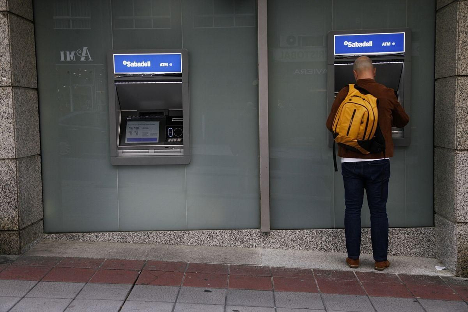 Un hombre saca dinero de un cajero de la ciudad.