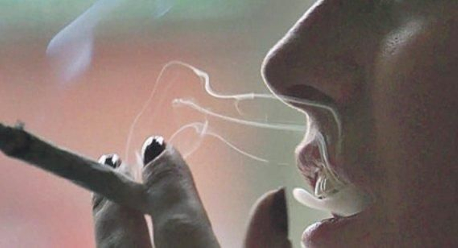 Una mujer joven fuma un cigarrillo.