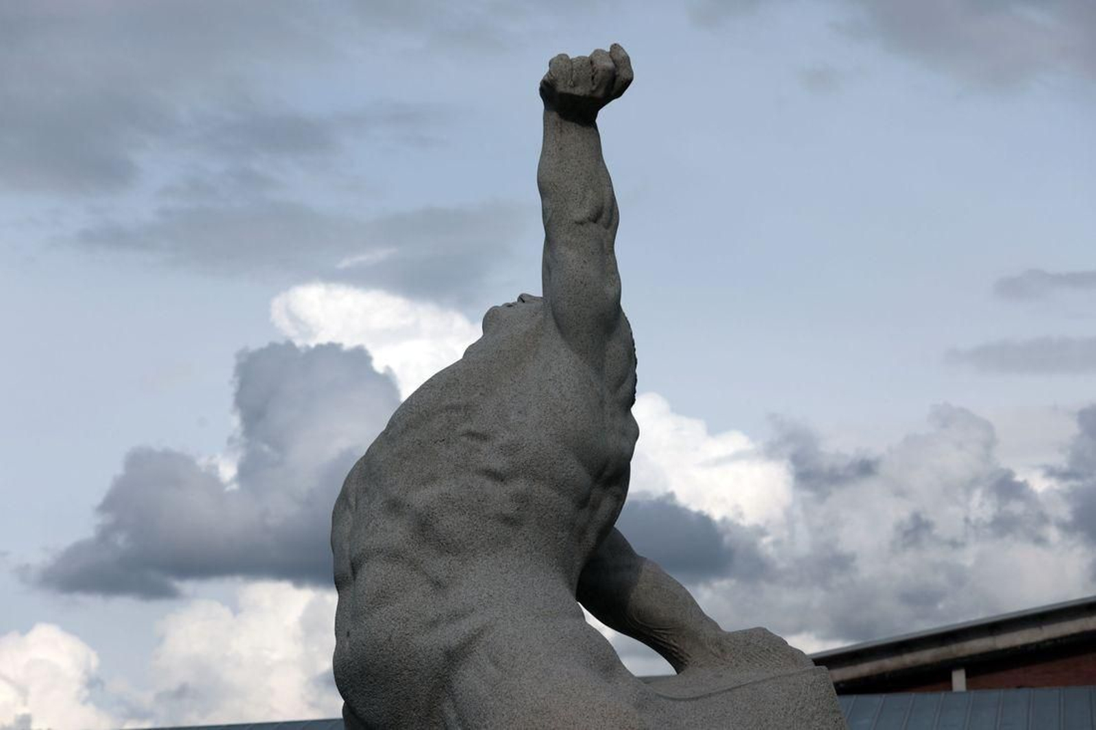 NEXUS 6 | El despertar del imponente granito de Carrera al final del Puente del Milenio invitaba a hacer lo propio con la ciudad; eran otros tiempos, año 2002, en el que se incorporaron al patrimonio urbano buen número de piezas. La mole de piedra con el torso desnudo de una figura humana sigue cargada de fuerza, por su expresividad y sugerente imagen ambigua que invita a completarla desde la propia mirada. Es, sin duda, una icónica imagen de la ciudad, representada en infinidad de ocasiones junto al propio puente. Por Xosé Lois Carrera.
