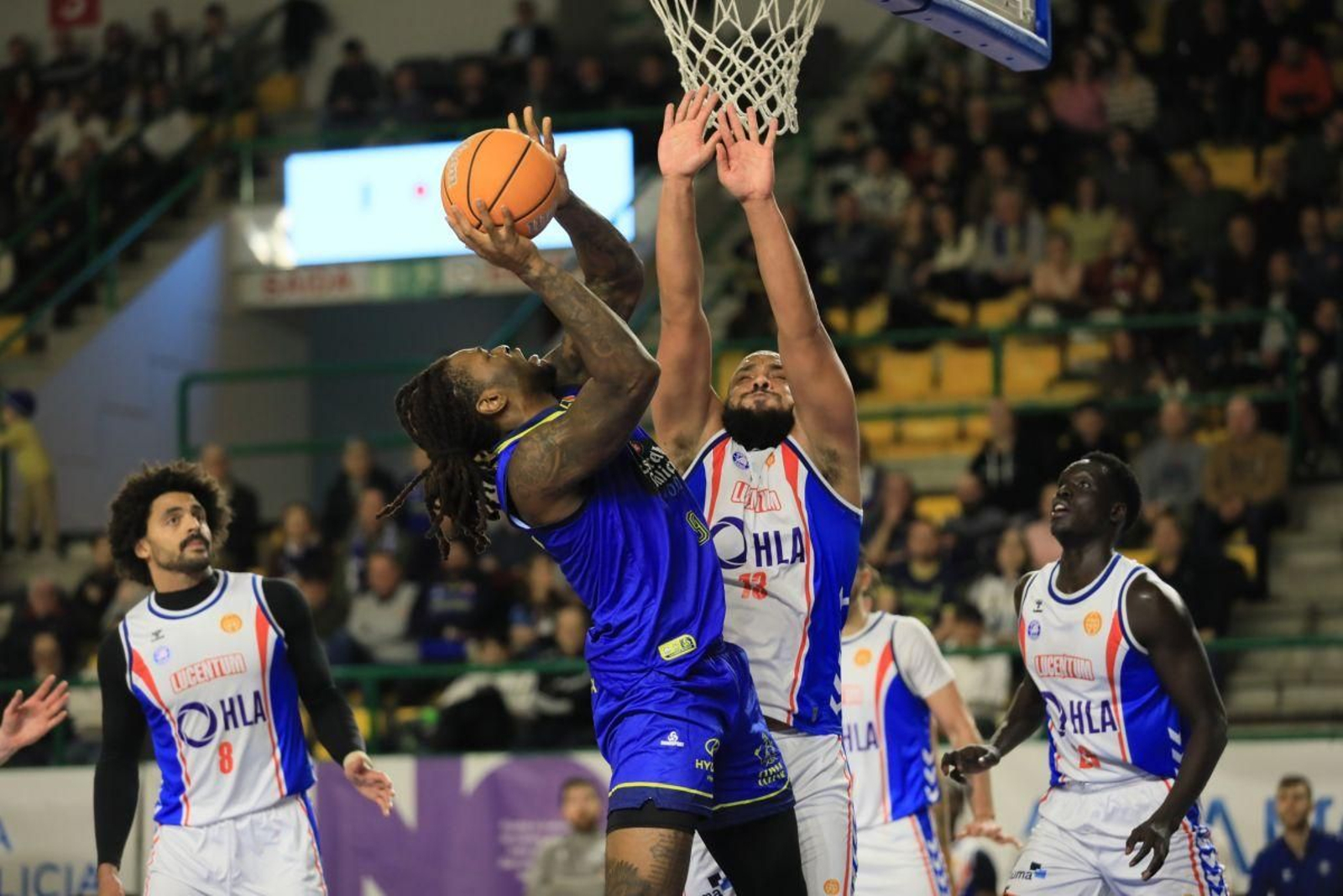 El cobista Okanu trata de lanzar a canasta ante la oposición de Larsen.