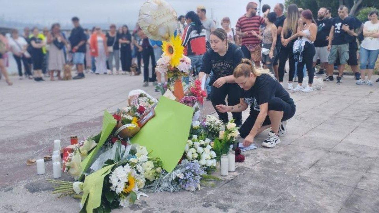 Homenaje floral al joven marinero fallecido en el lugar del accidente: en la imagen, su novia junto a las flores rodeada de familiares y amigos.