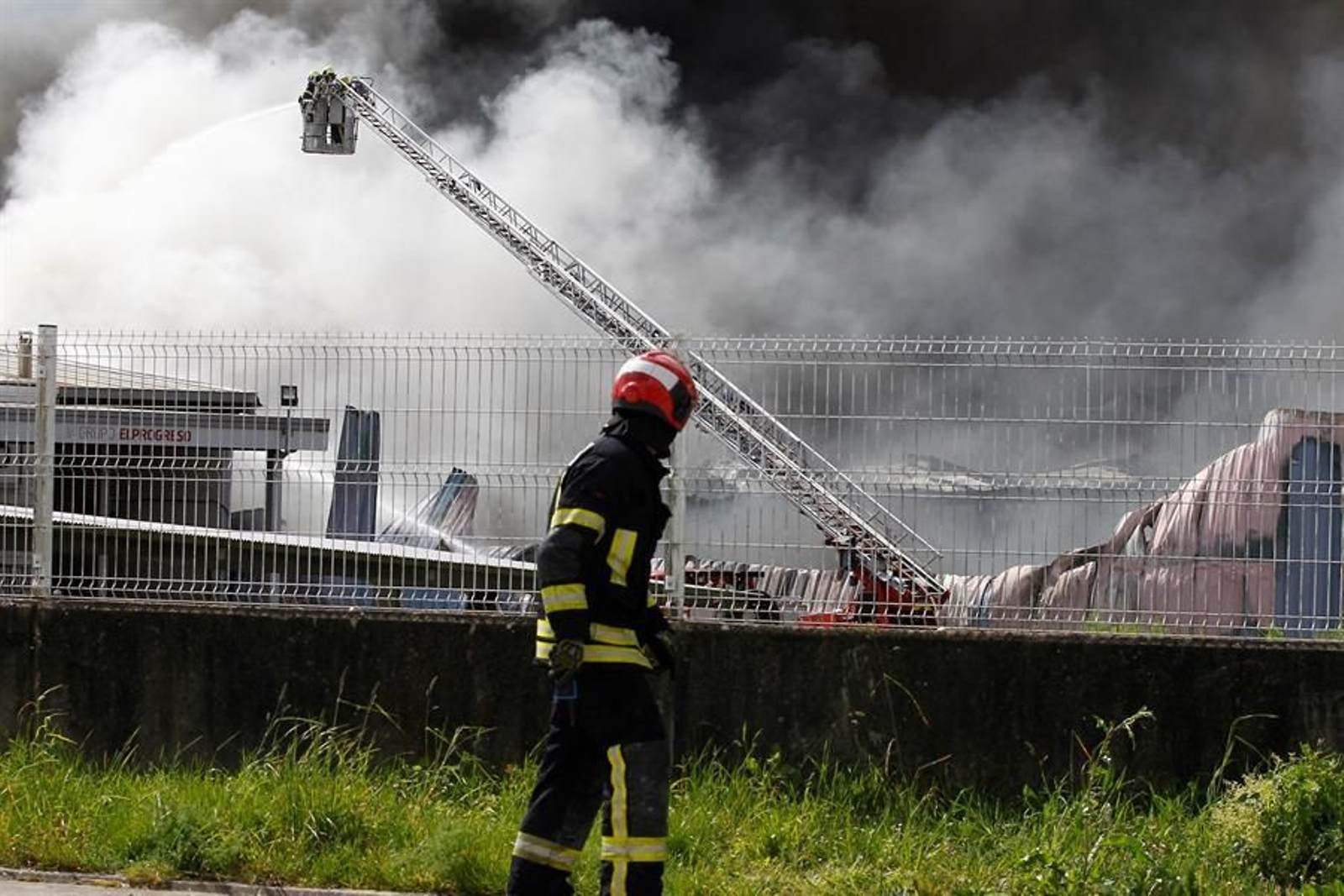 Varios bomberos intentan controlar las llamas de un incendio en el parque empresarial de O Ceao, este domingo. El secretario general del Confederación de Empresarios de Lugo (CEL), Jaime López, ha calificado este domingo como "un día negro para Lugo" por el incendio que ha calcinado al menos cuatro naves en el polígono industrial de O Ceao y que ha obligado a activar el nivel 1 del plan de emergencias de Galicia, aunque no ha provocado daños personales. EFE/Eliseo Trigo