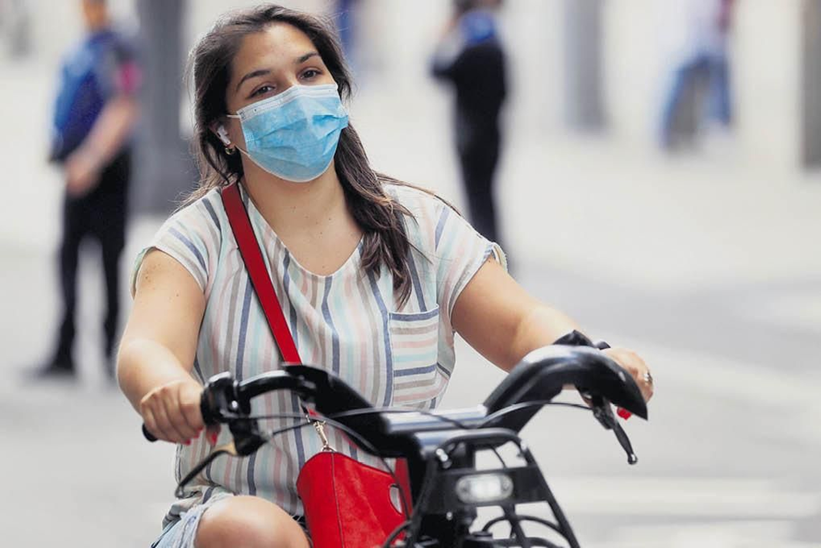 Una mujer con mascarilla, circula en bicicleta por una calle de Madrid.