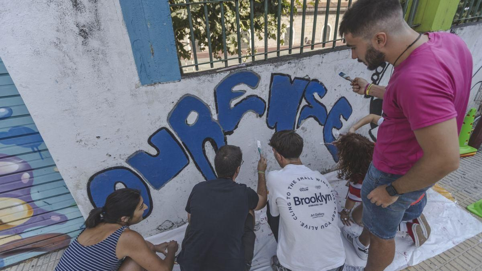 Voluntarios de Amencer actualizando el muro de la calle Saenz Diez.