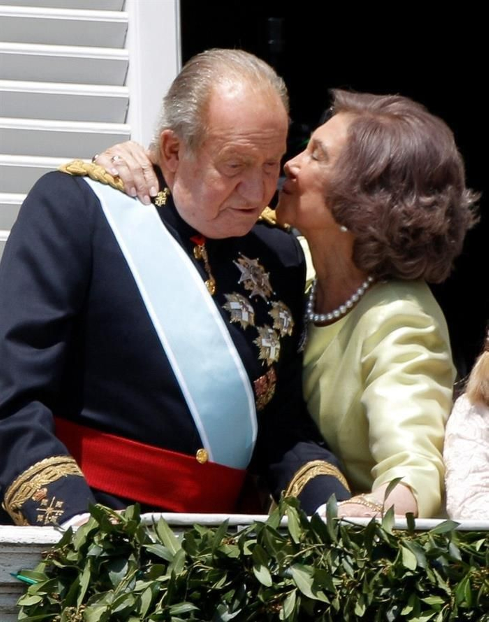 Doña Sofía besa a Don Juan Carlos en el balcón central del Palacio Real donde han acompañado al Rey Felipe VI