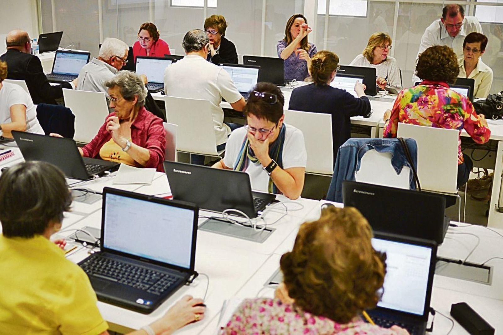 Un grupo de mayores aprende el uso de ordenadores.