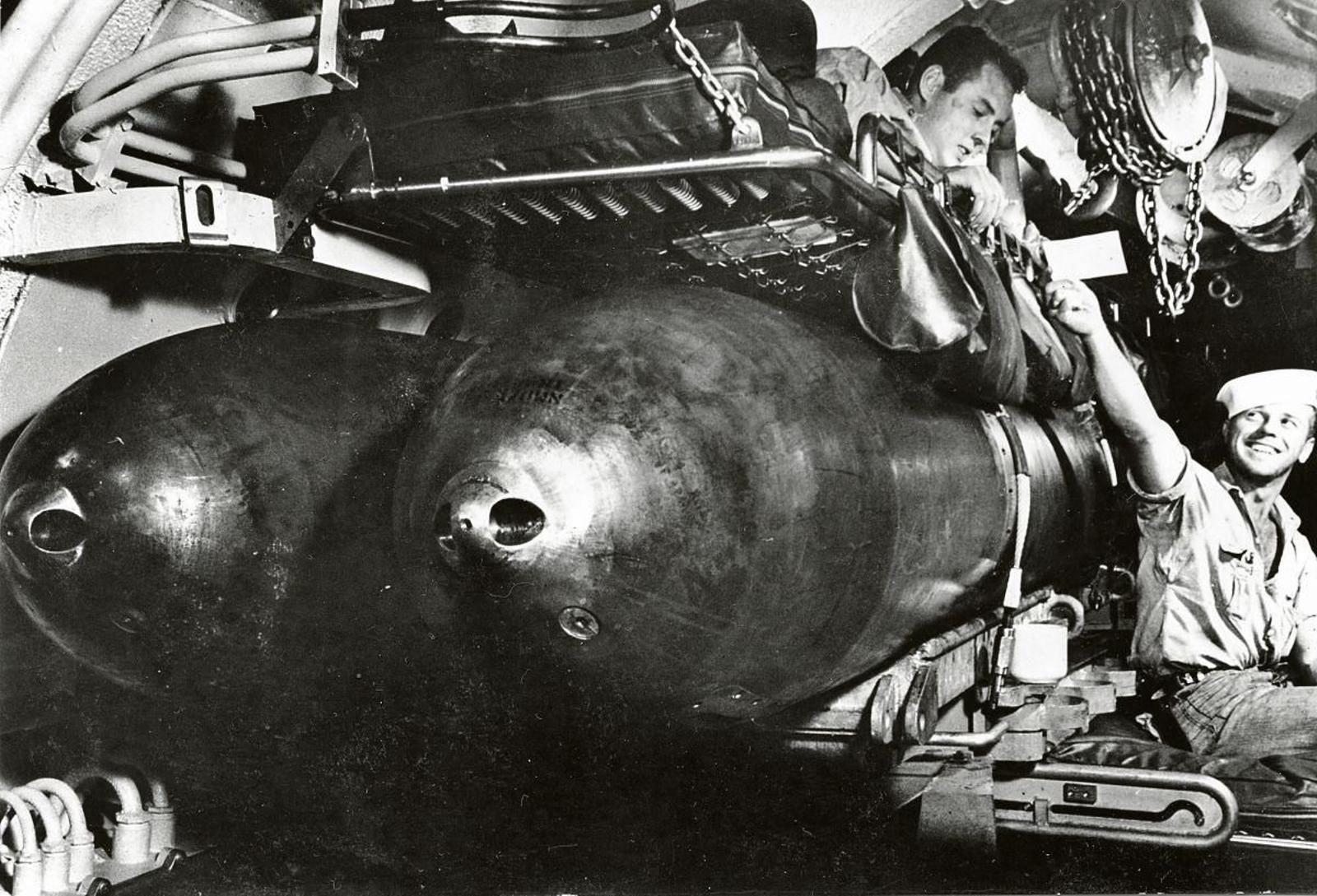 Marineros compartiendo espacio con torpedos en un submarino.