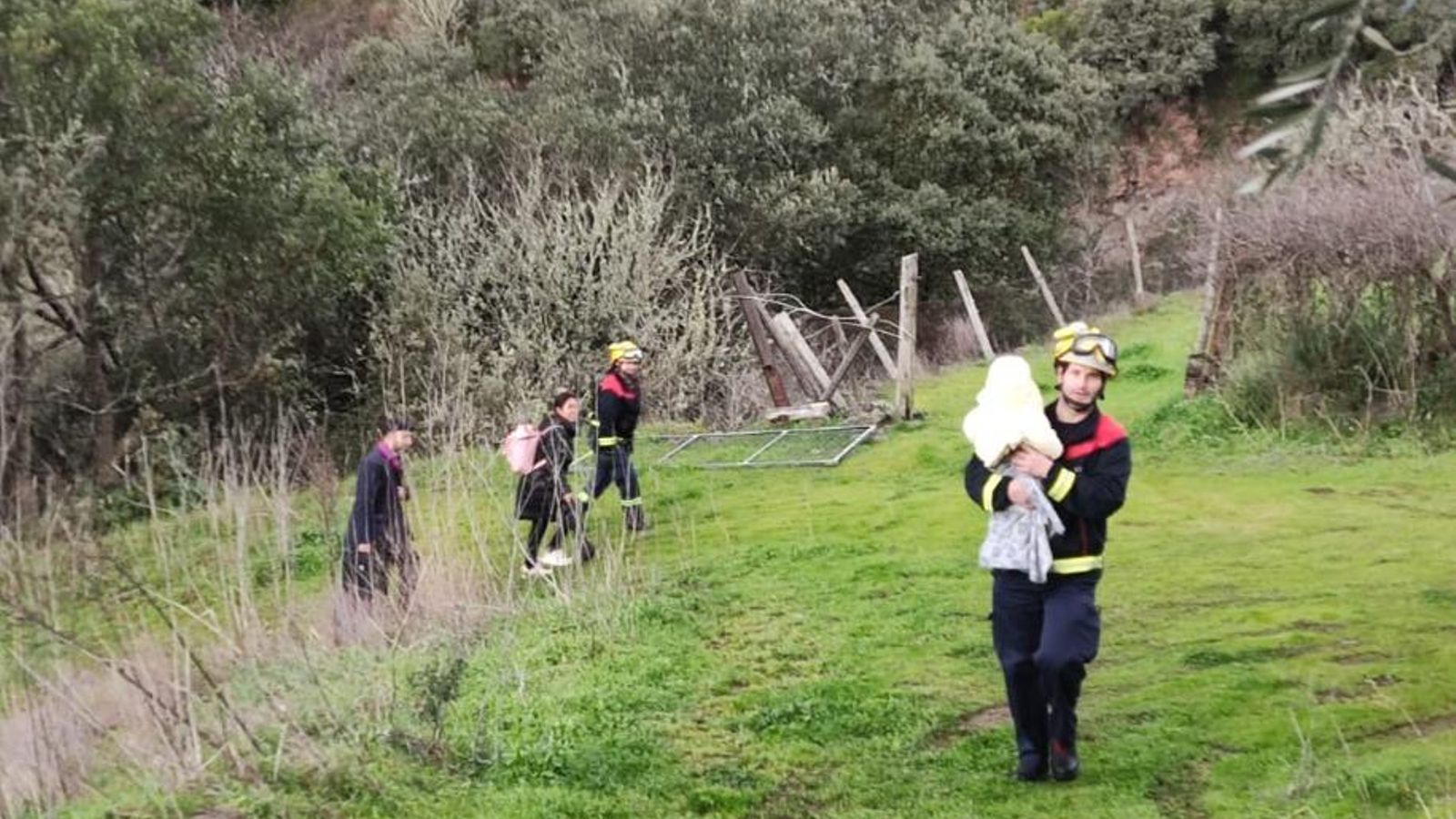 Carritos, maletas y un bebé en manos de un miembro del GES abandonan la zona de la vía montaña arriba.