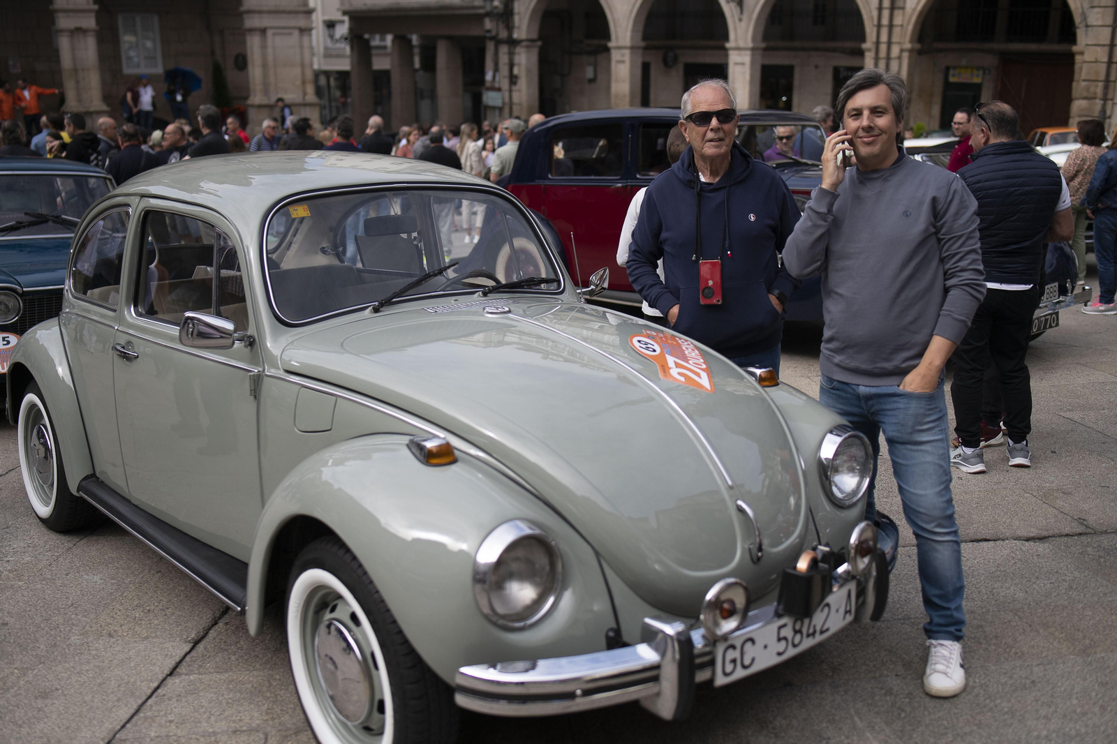 2 personas posando para la foto con un coche de rally antiguo en Ourense