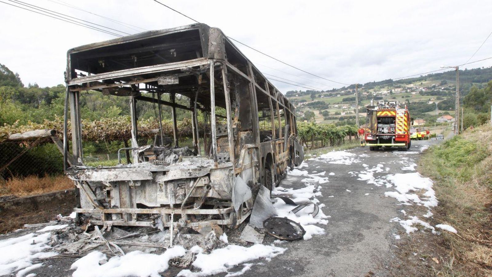 El autobús, completamente calcinado en la parroquia de Aríns.