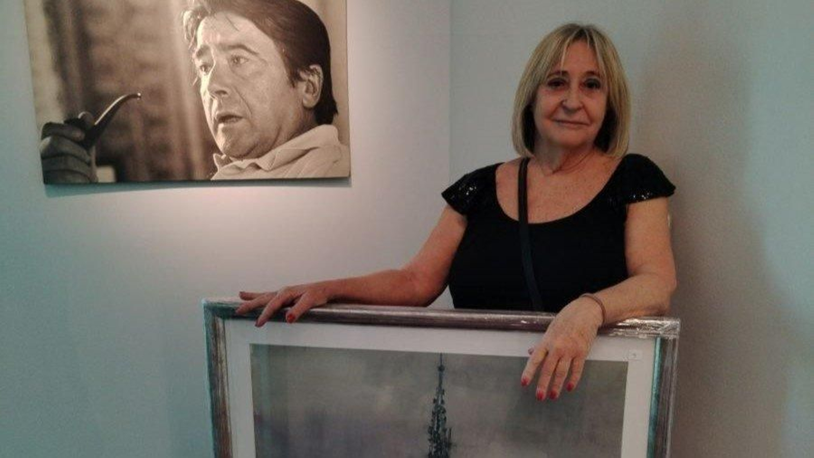 Teresa Pérez, viuda de Rafael Alonso, posa con un cuadro ante la fotografía del artista.