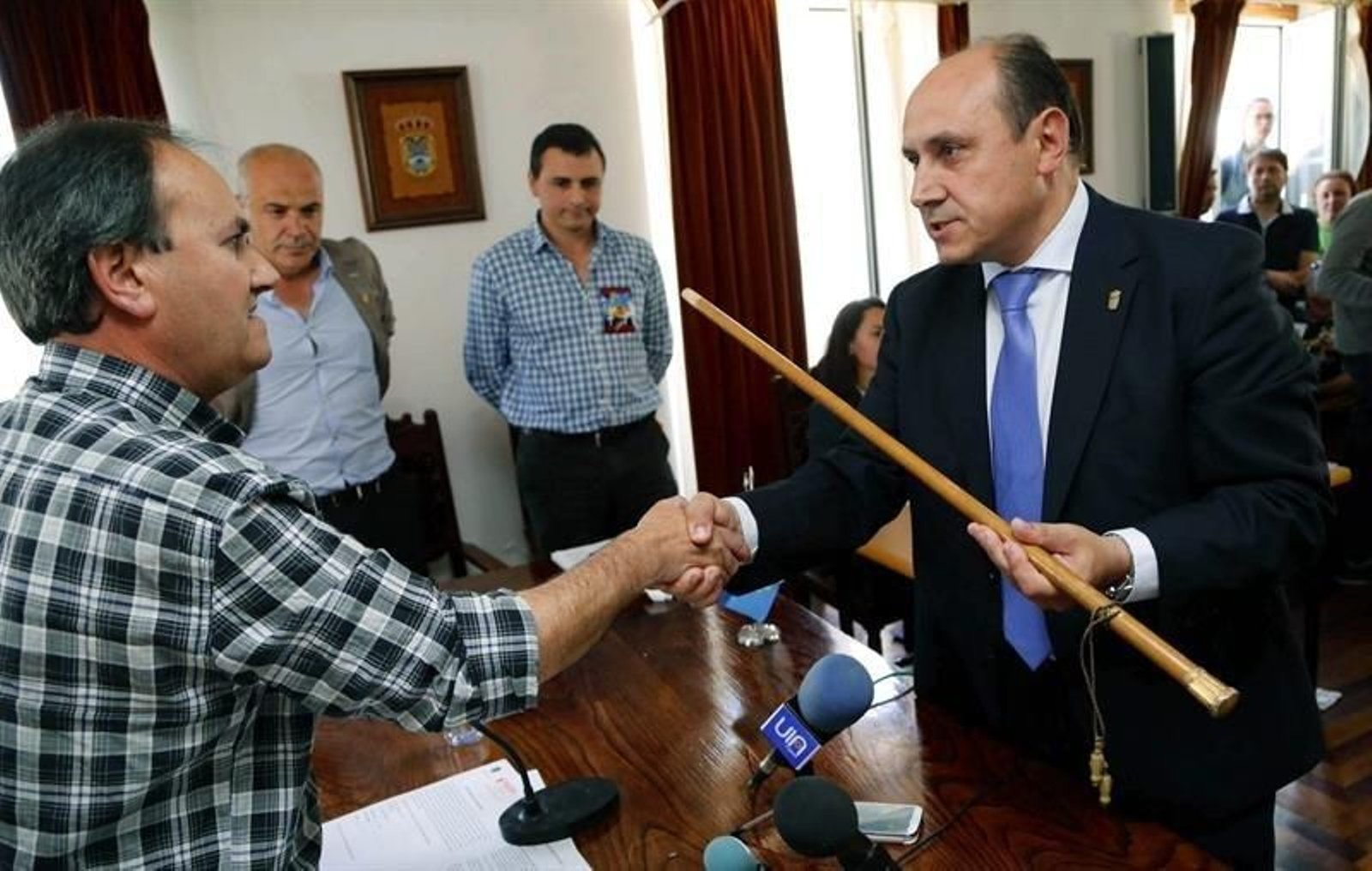 El nuevo alcalde de Arbo, Horacio Gil (d), recibe el bastón de mando del concejal de mayor edad, al prosperar la moción de censura. (EFE)