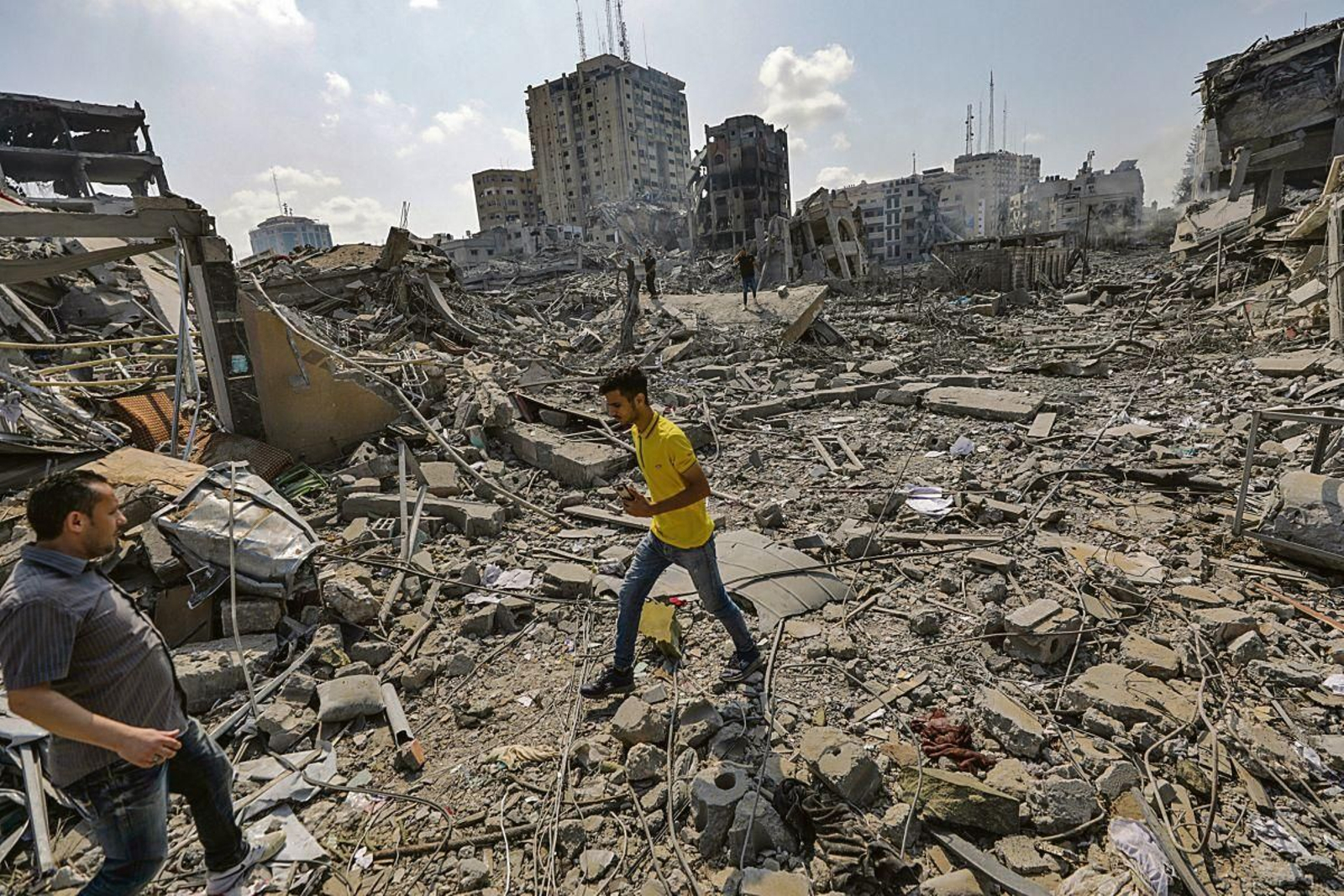 Palestinos caminan entre los escombros del destruido barrio de Al-Ramal tras un ataque aéreo israelí, ayer en la ciudad de Gaza.
