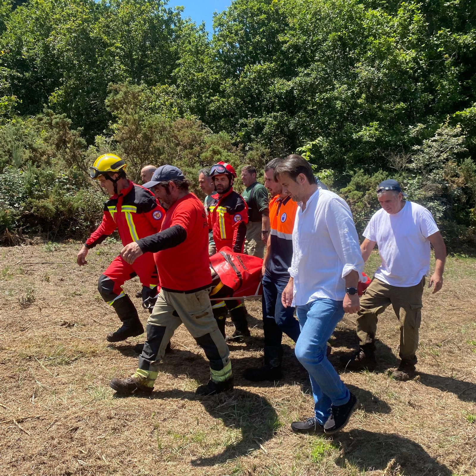 Voluntarios y agentes de la brigada forestal de la Xunta transportan al anciano, envuelto en mantas para combatir el principio de hipotermia.