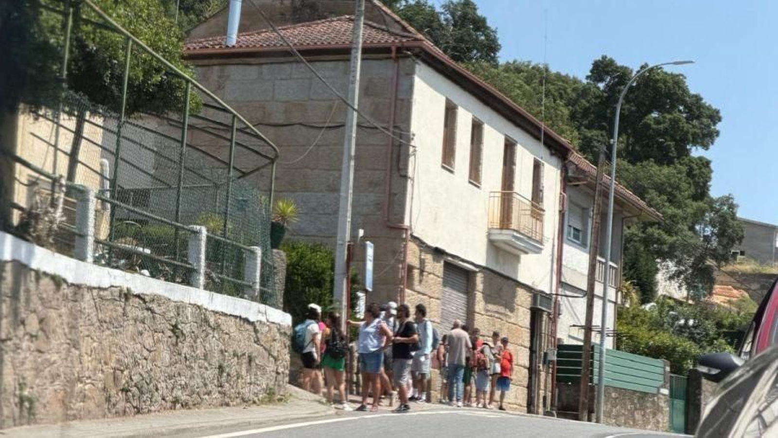 Gente amontonada en la parada de bus para volver de las piscinas de Oira