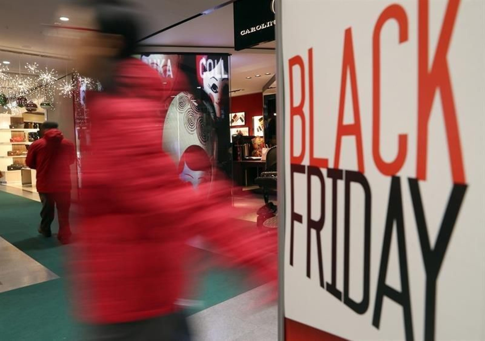 Un hombre pasa ante un cartel publicitario que hace alusión al 'Black Friday' hoy en un conocido centro comercial de la capital. (GUILLÉN)