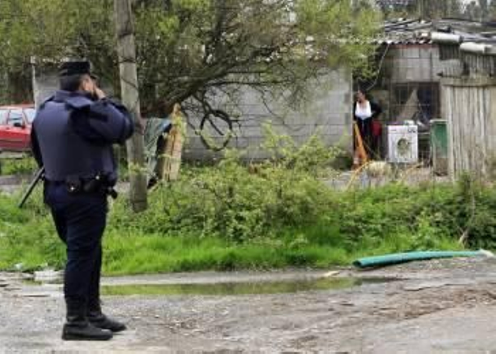 Un agente de Policía vigila el asentamiento situado en Freixeiro, en el concello coruñés de Narón. (Foto: KIKO  DELGADO)