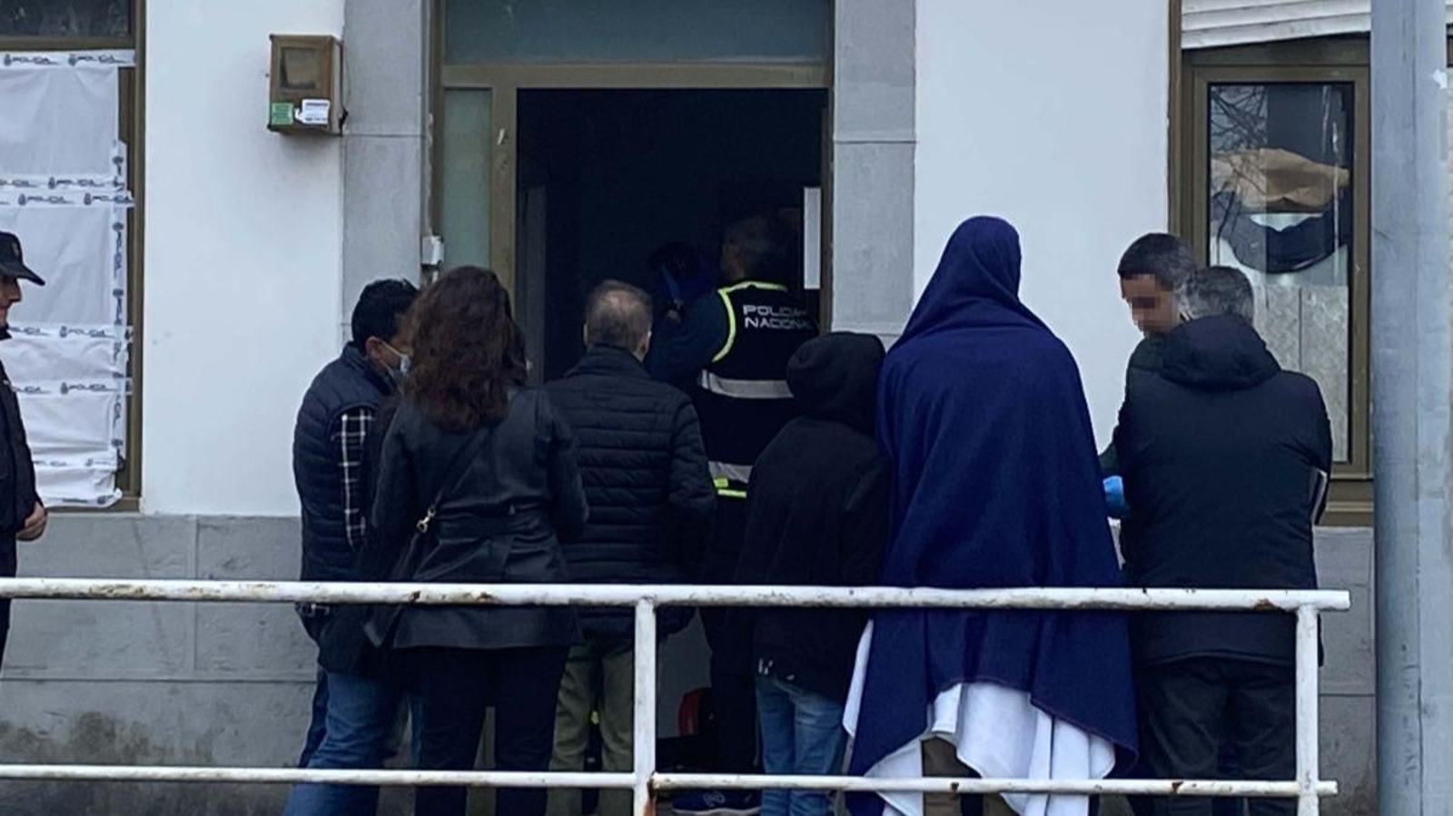 La pareja detenida (de espaldas y cubierta) a la entrada del registro en la vivienda en la avenida  Atlántida.