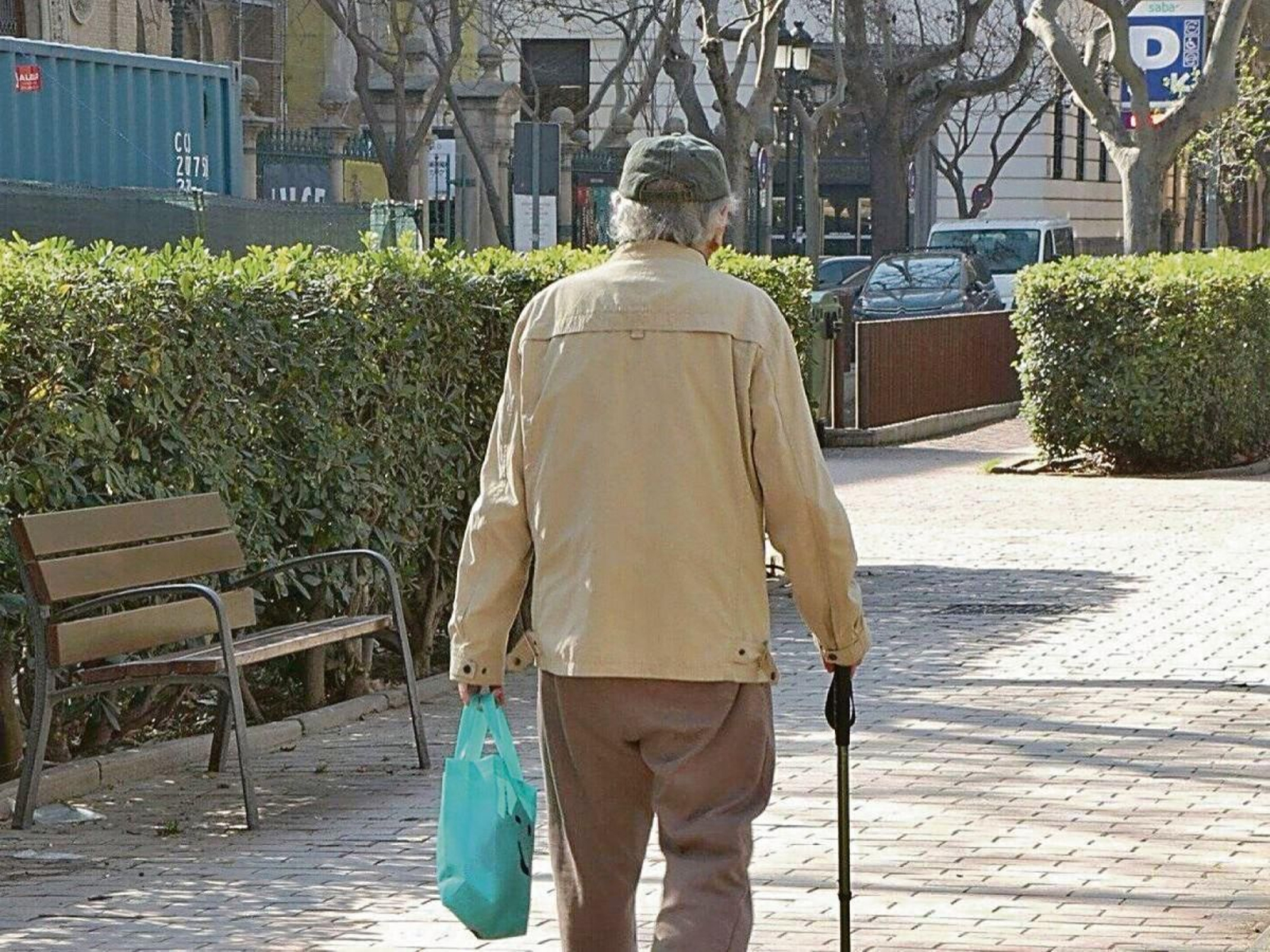 Una persona mayor pasea por un parque.