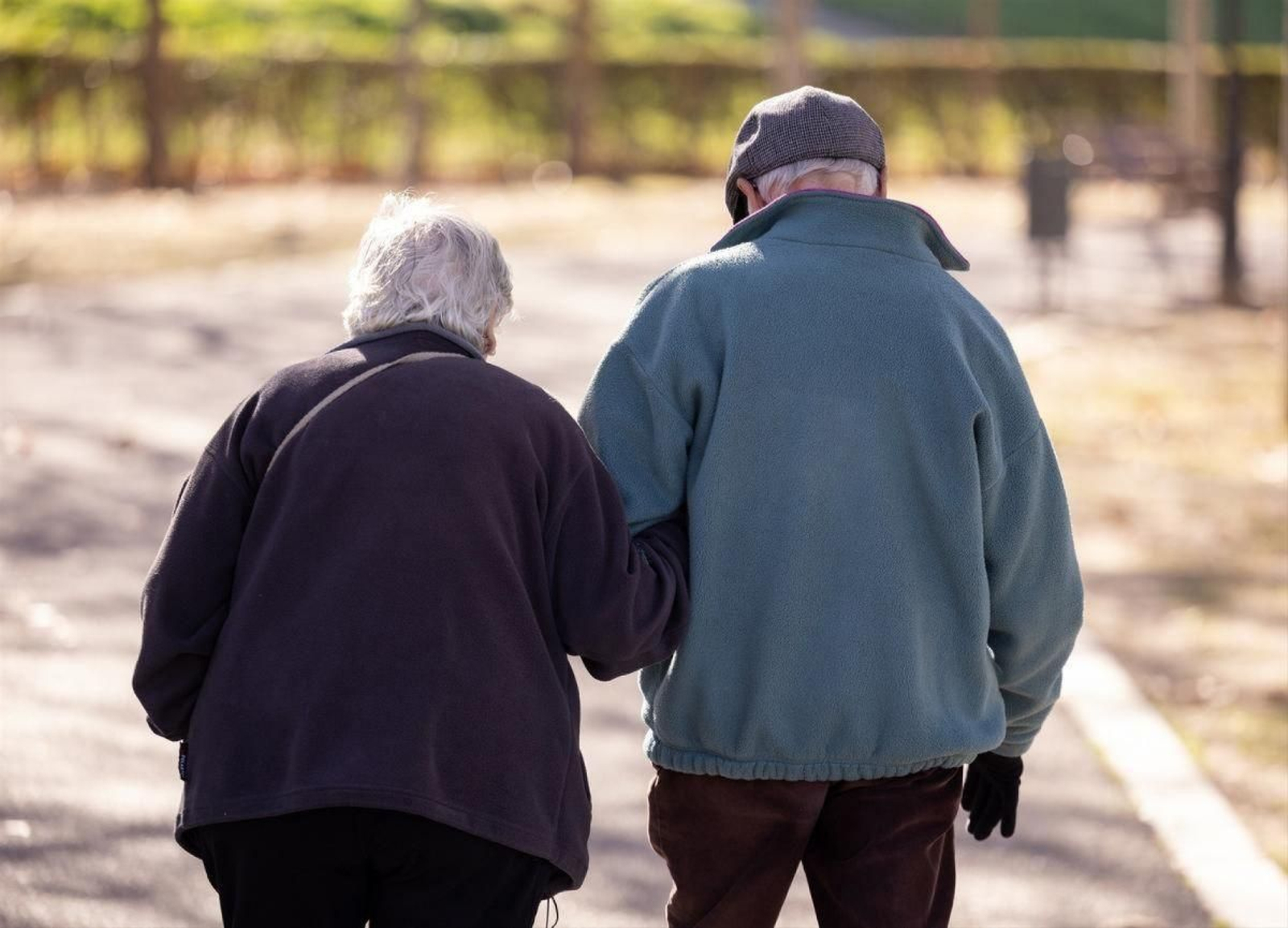 Dos personas mayores pasean por un parque de Madrid.