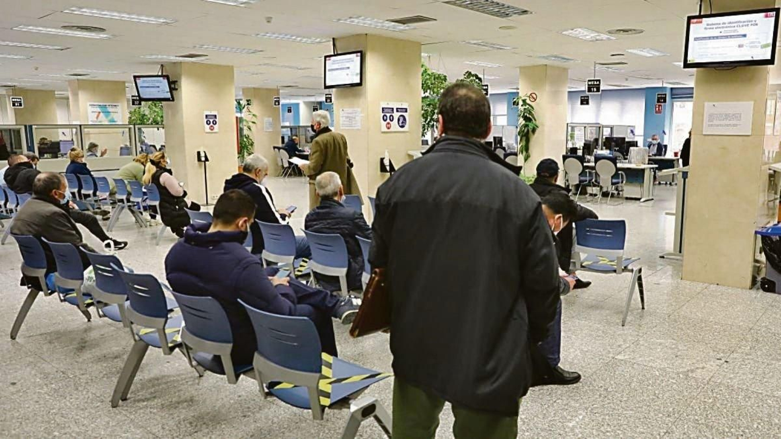 Varias personas esperan en una oficina de Hacienda.