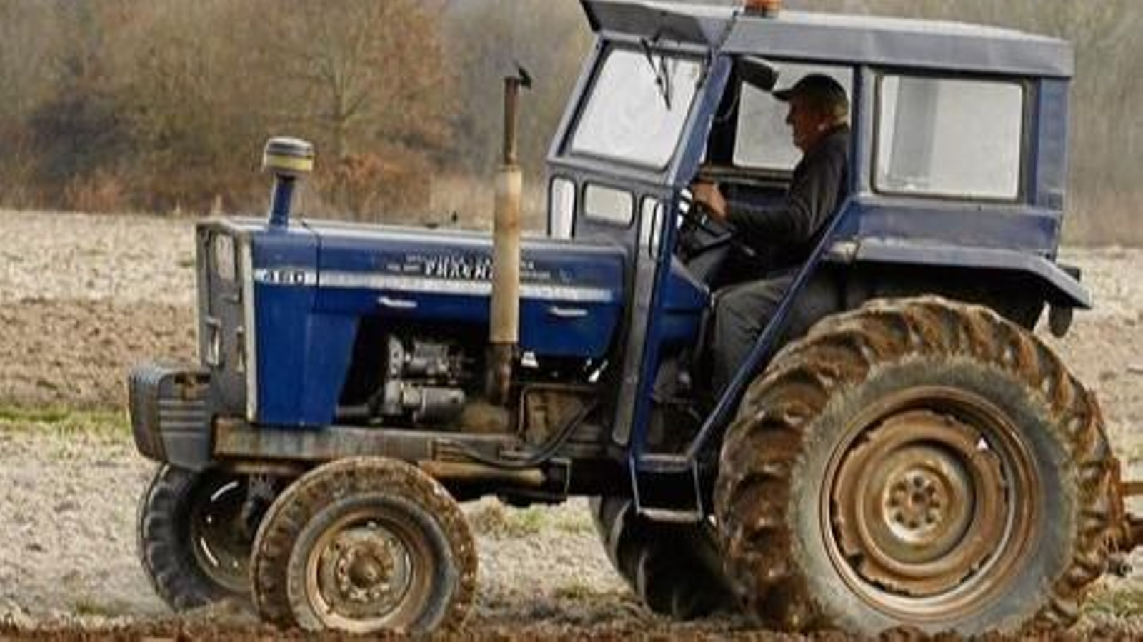 Un hombre trabaja una finca al pie de la torre de Sandiás.