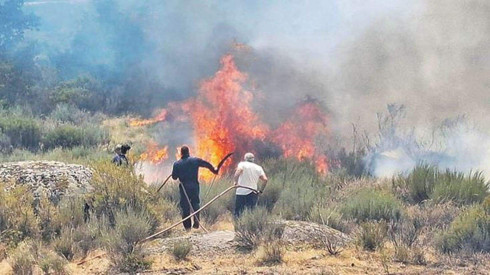 Varios vecinos voluntarios apagaban el fuego junto a las viviendas en O Pereiro.