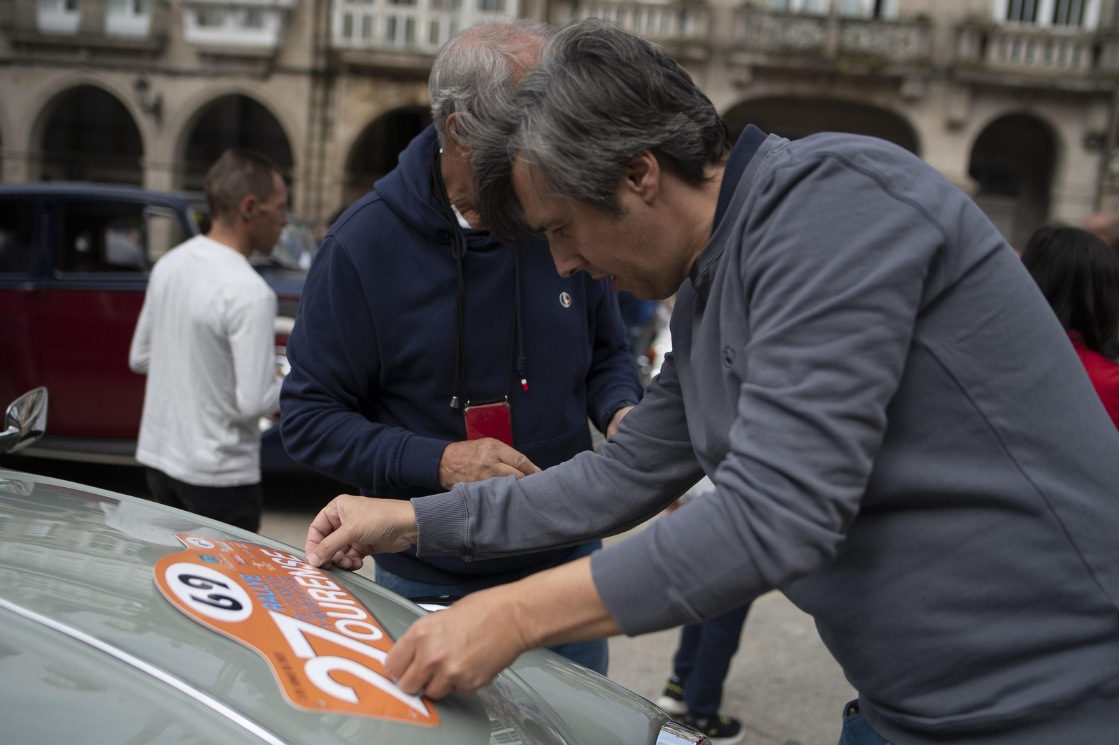Señor colocando una pegatina de la 27 edición de coches de rally clásicos en Ourense