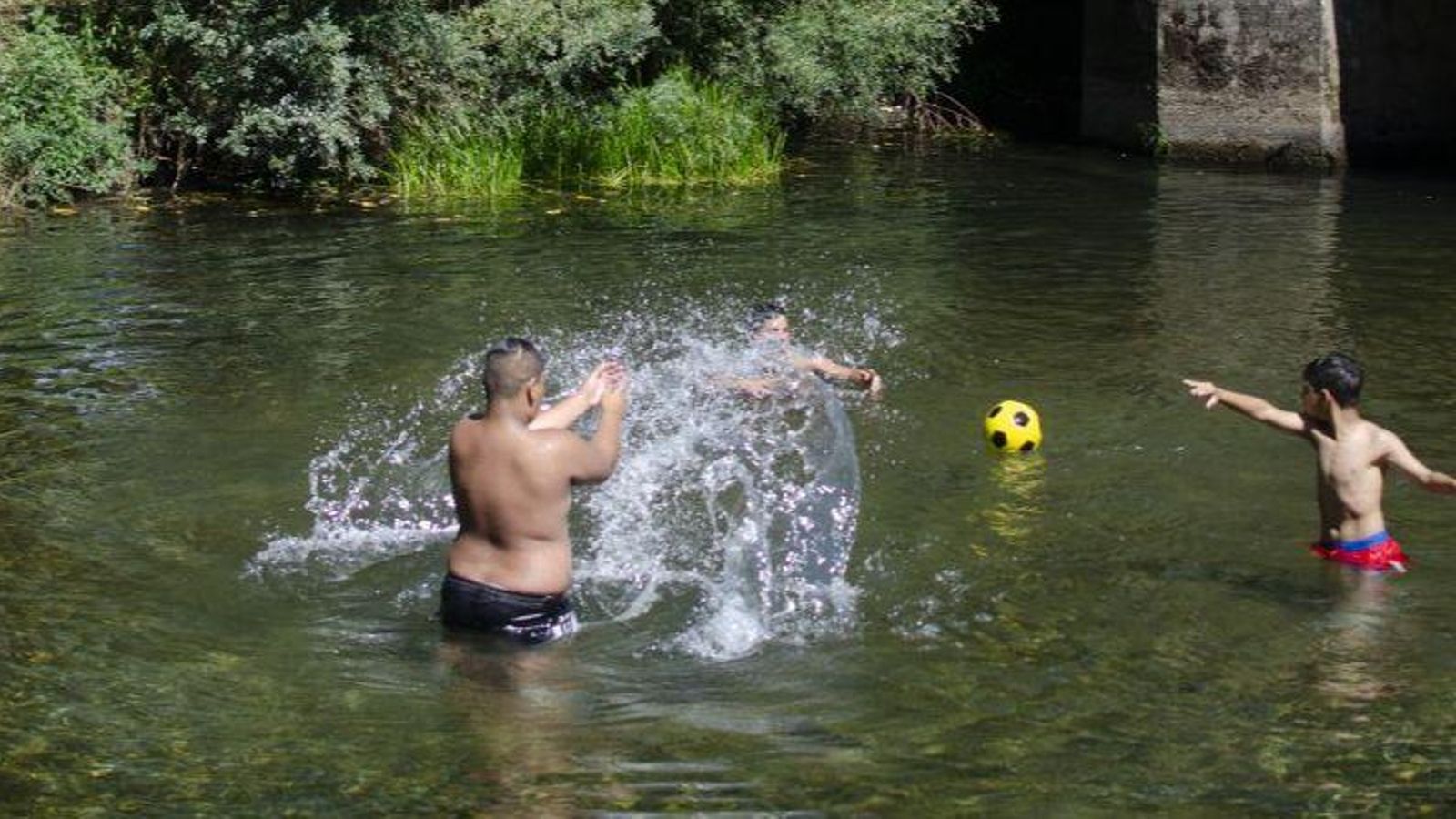 Un grupo de jóvenes se refresca en un río.