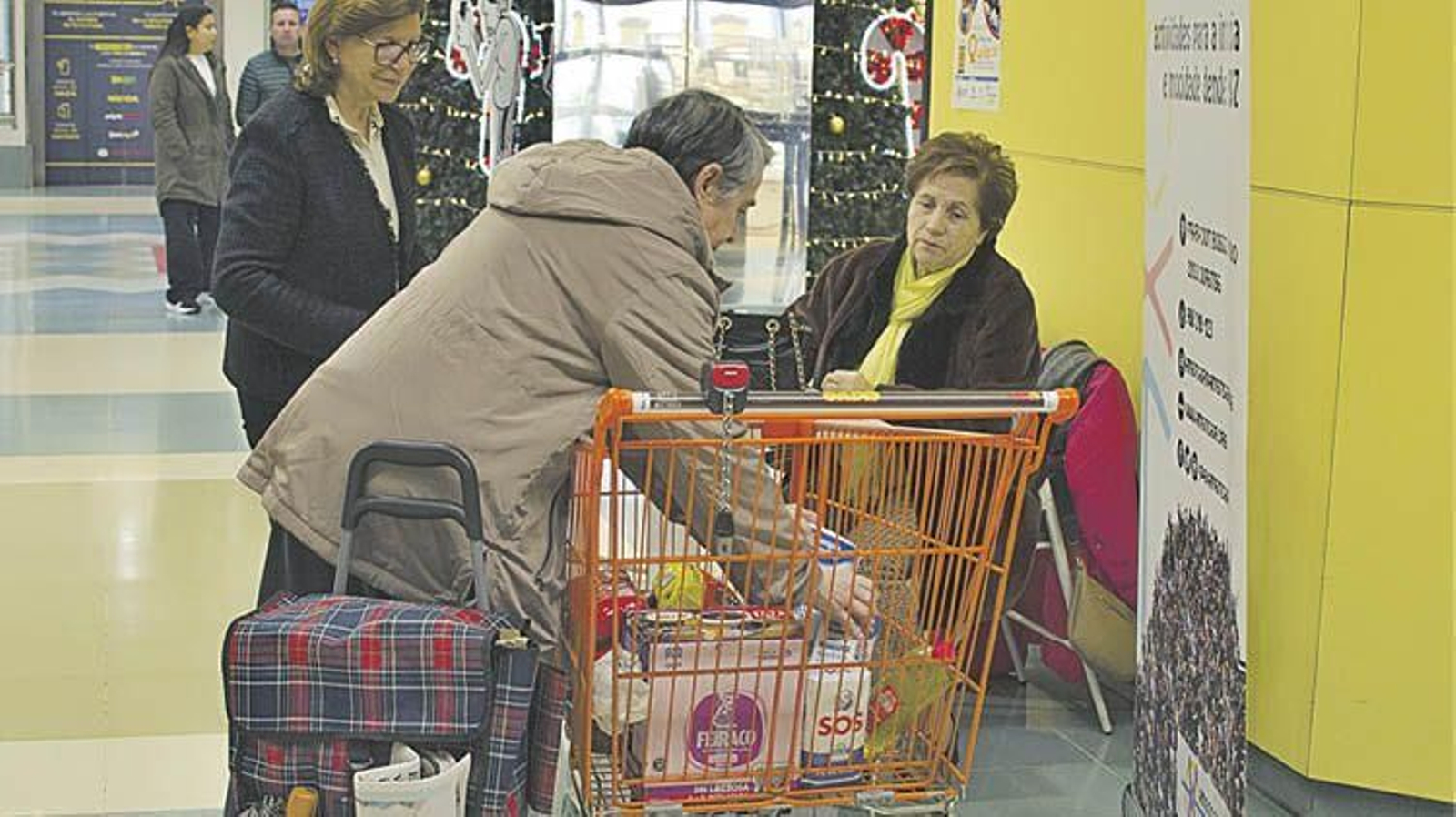 Un ciudadano deposita una donación en un carro de la Operación Quilo.