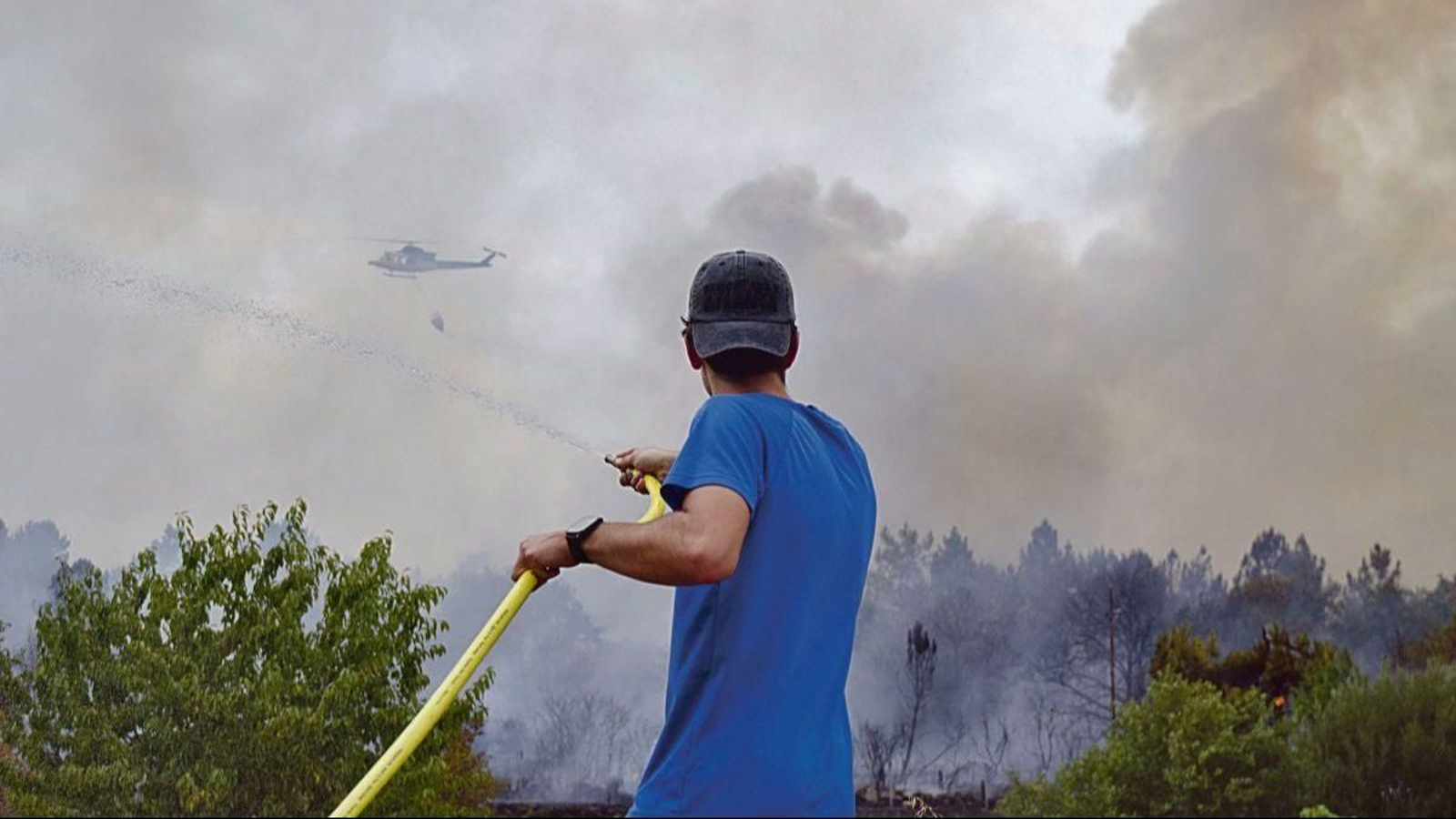 Un vecino de Ponte Noalla protege su vivienda, en un incendio propagado por una finca sin limpiar.