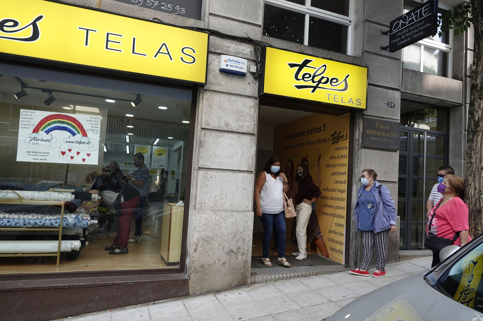 Los clientes hacen cola para entrar a una tienda a comprar telas, en el centro de Vigo.