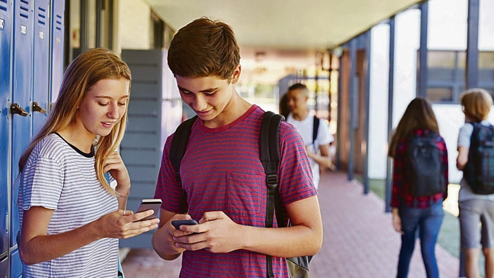 Dos menores de edad hacen uso de “smartphones” en el instituto.