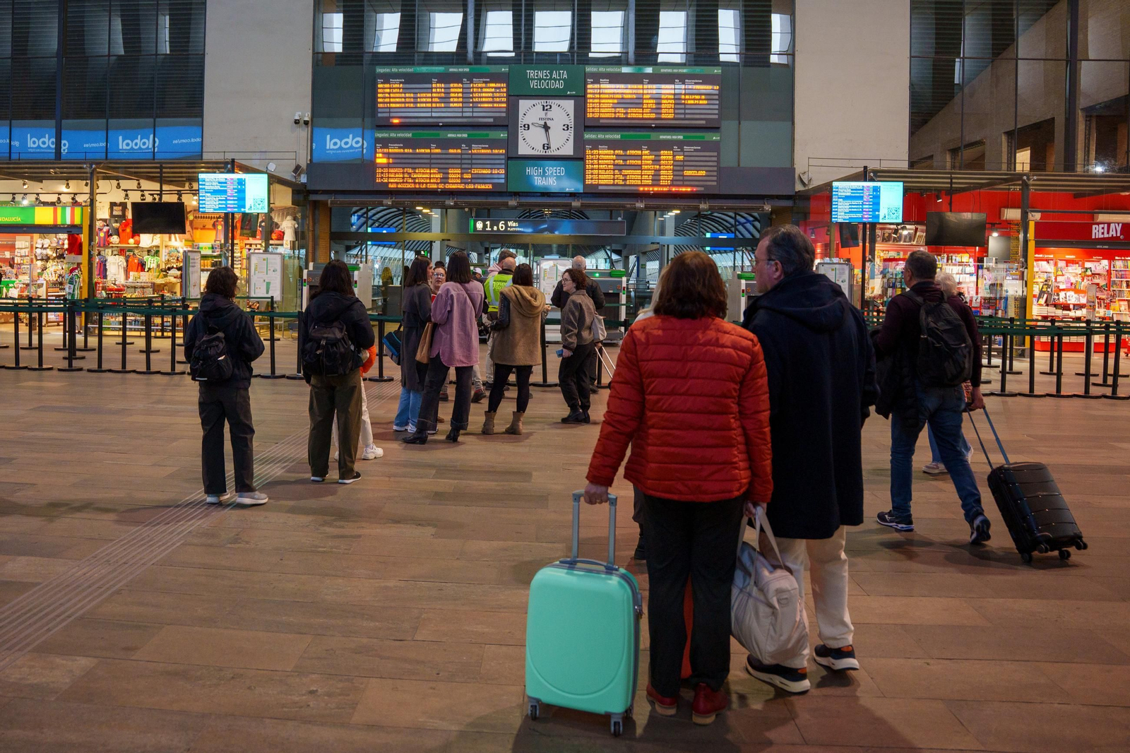 Viajeros en el vestíbulo de la estación de trenes de Santa Justa de Sevilla esperando la salida de su tren.