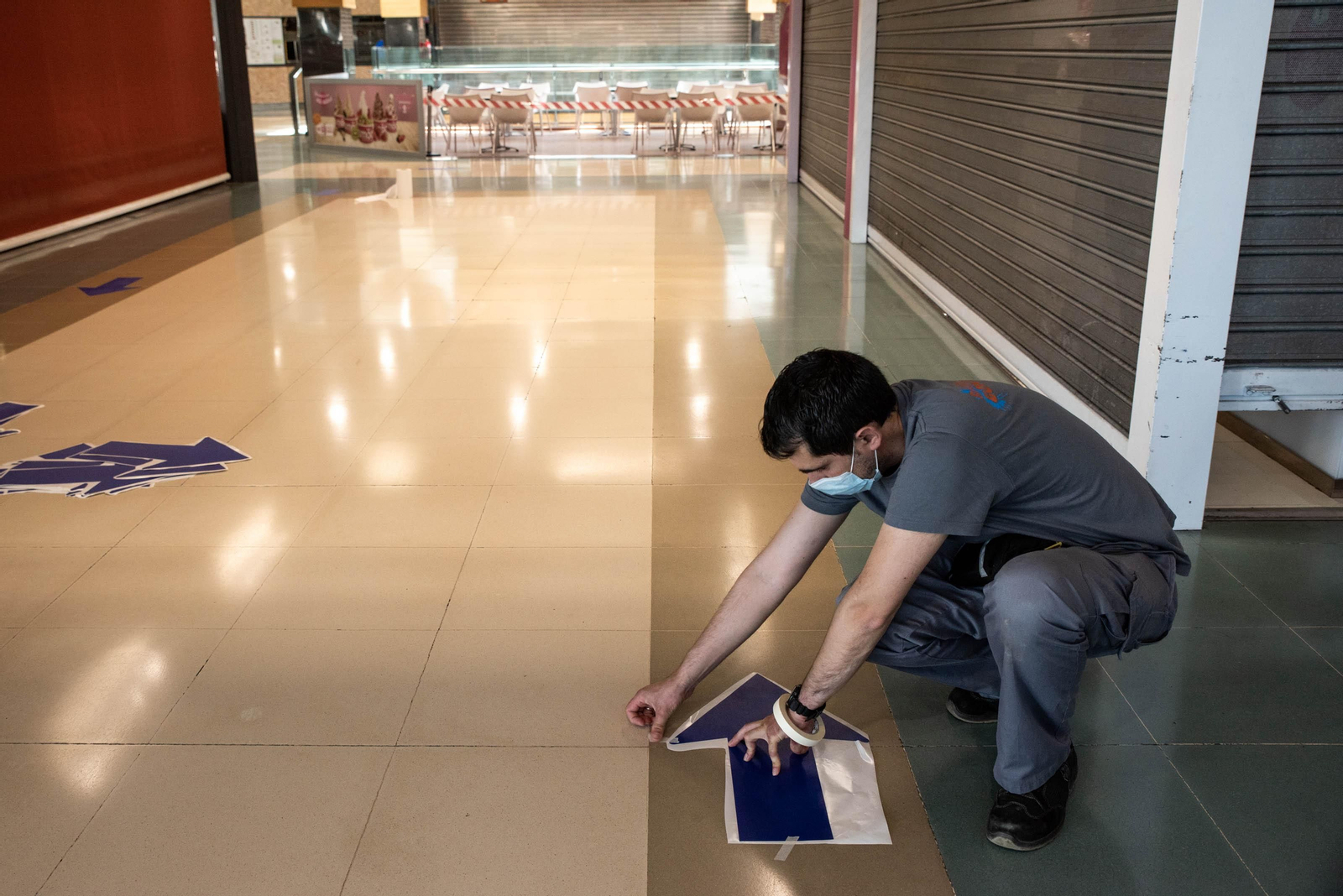 Un trabajador coloca indicaciones en el suelo del Centro Comercial Ponte Vella para mantener las distancias de seguridad. FOTO: ÓSCAR PINAL