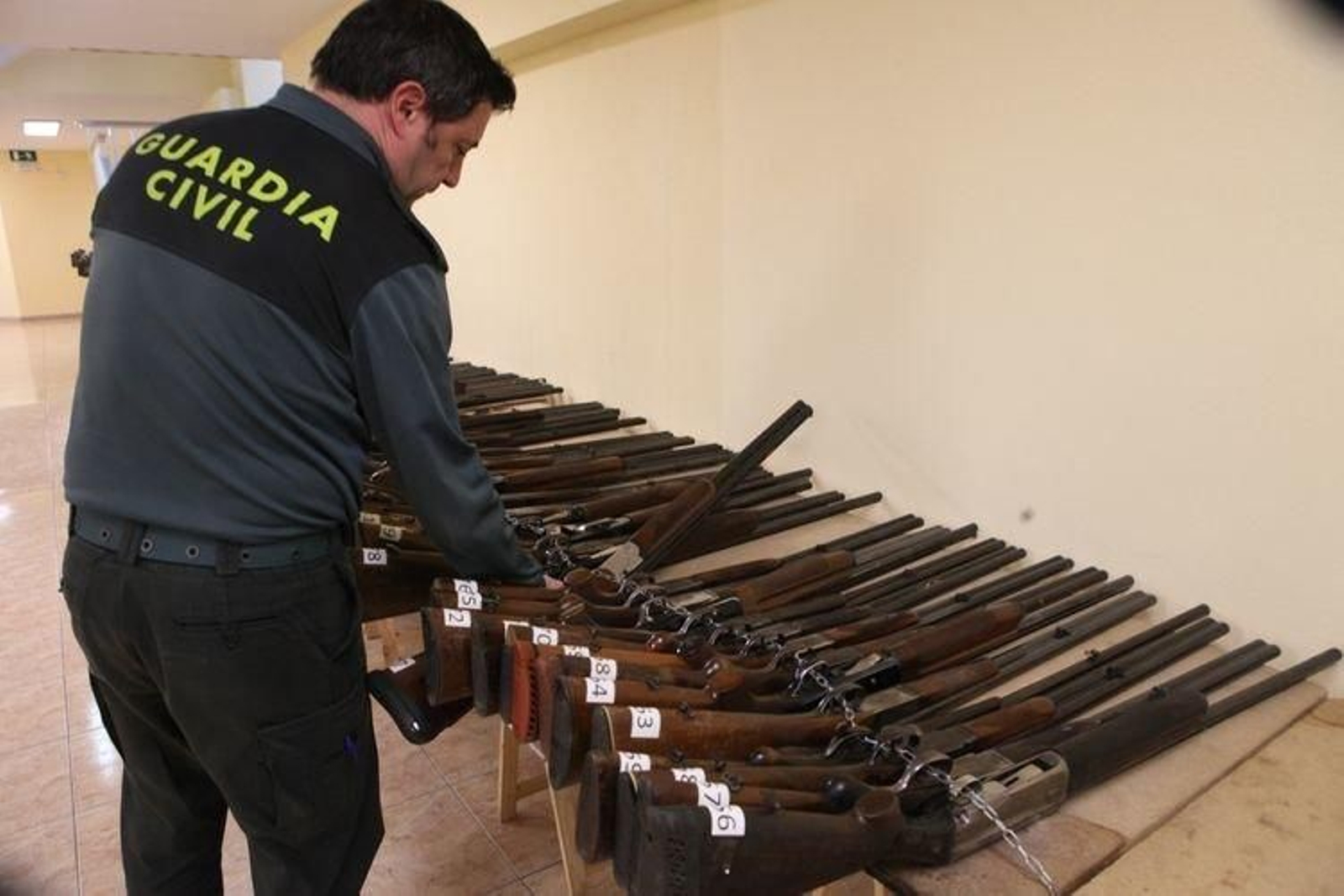 Un agente de la Guardia Civil, con parte de las armas a subasta. (MARCOS ATRIO)