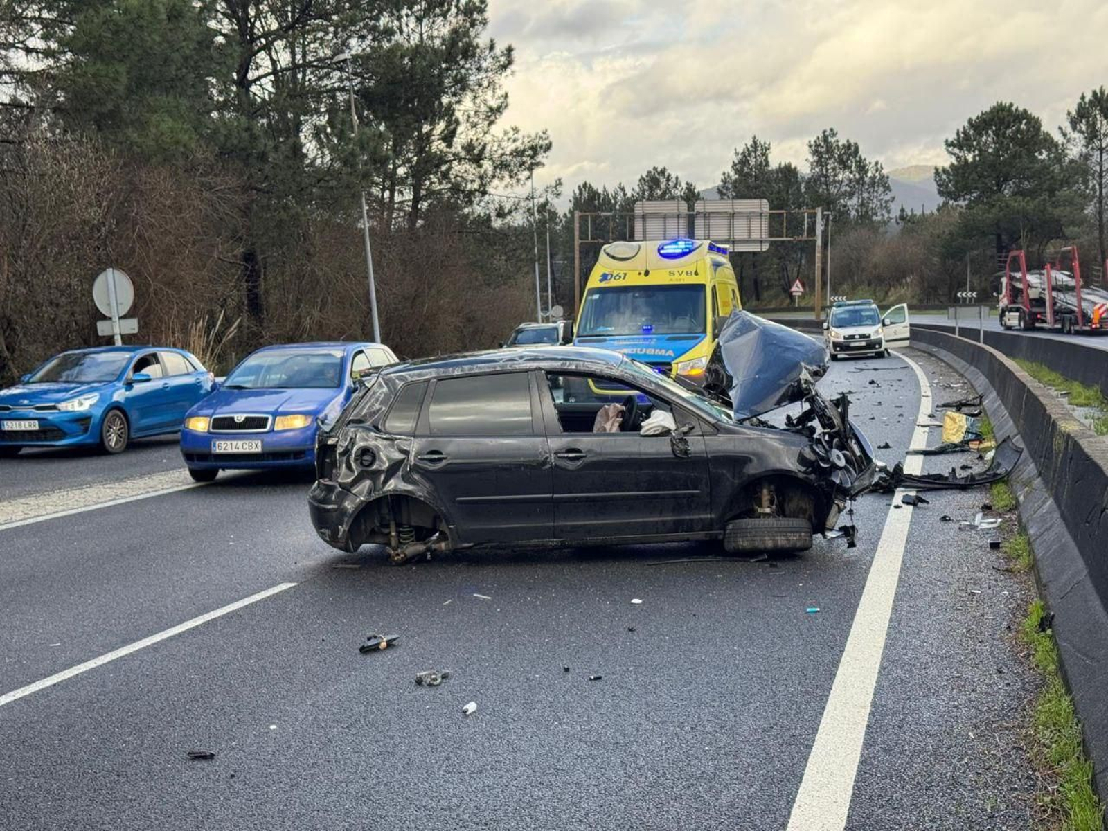 Los restos del coche esparcidos por la A-55 y la ambulancia en el punto.