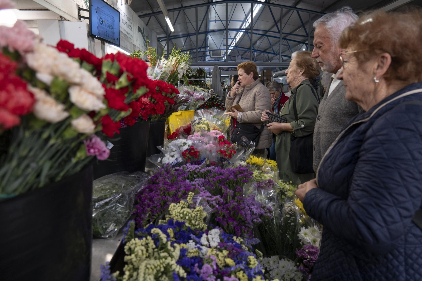 Un grupo de clientes compra flores en uno de los puestos de la Plaza de Abastos.