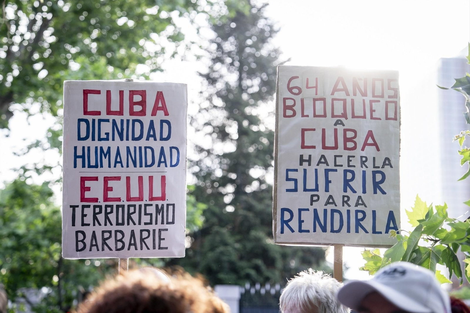 Varias personas con pancartas con lemas 'Cuba. Dignidad. Humanidad. EEUU. Terrorismo. Barbarie' y '64 años bloqueo a Cuba.