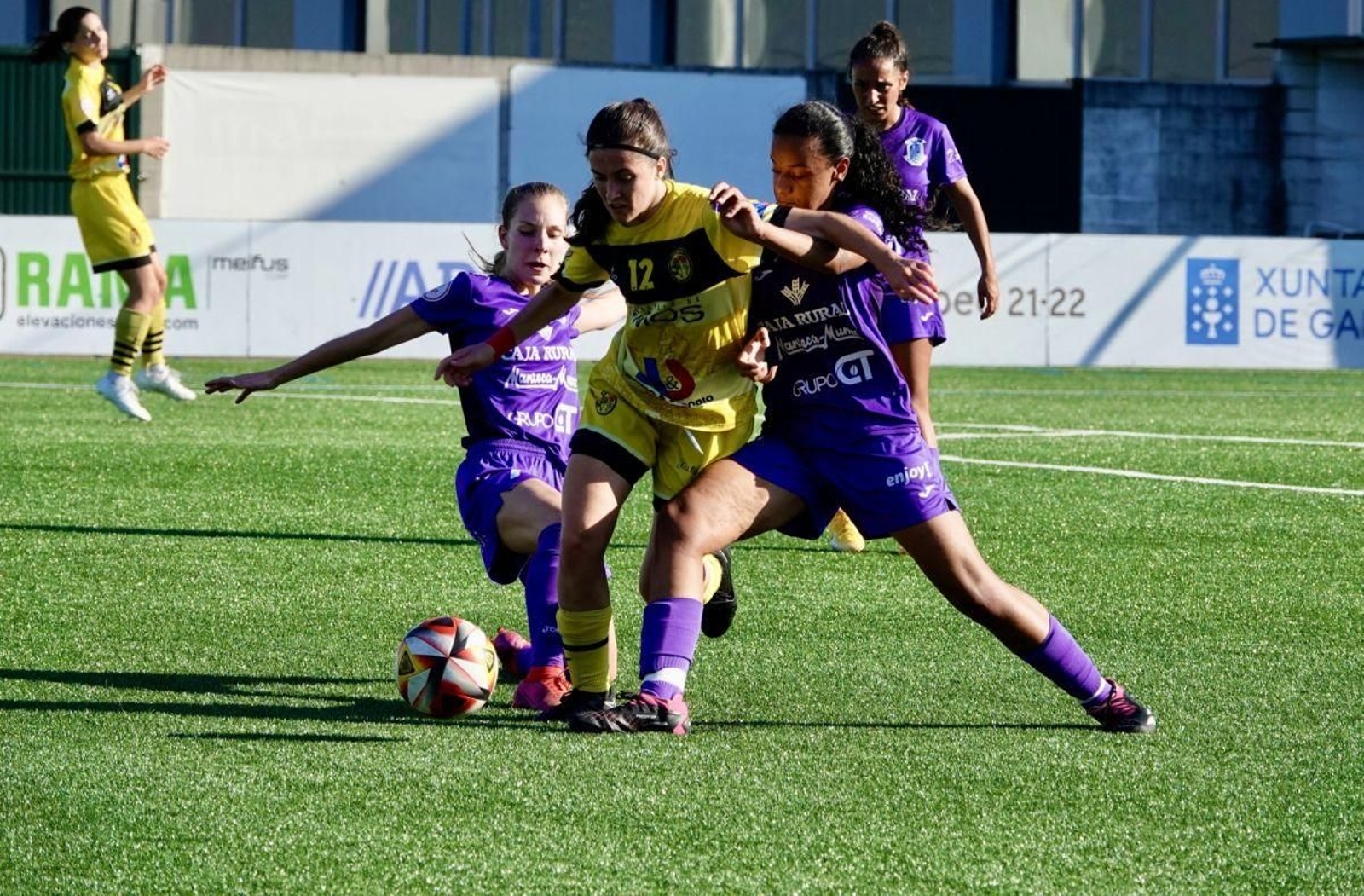 Celia trata de llevarse el balón entre dos rivales.