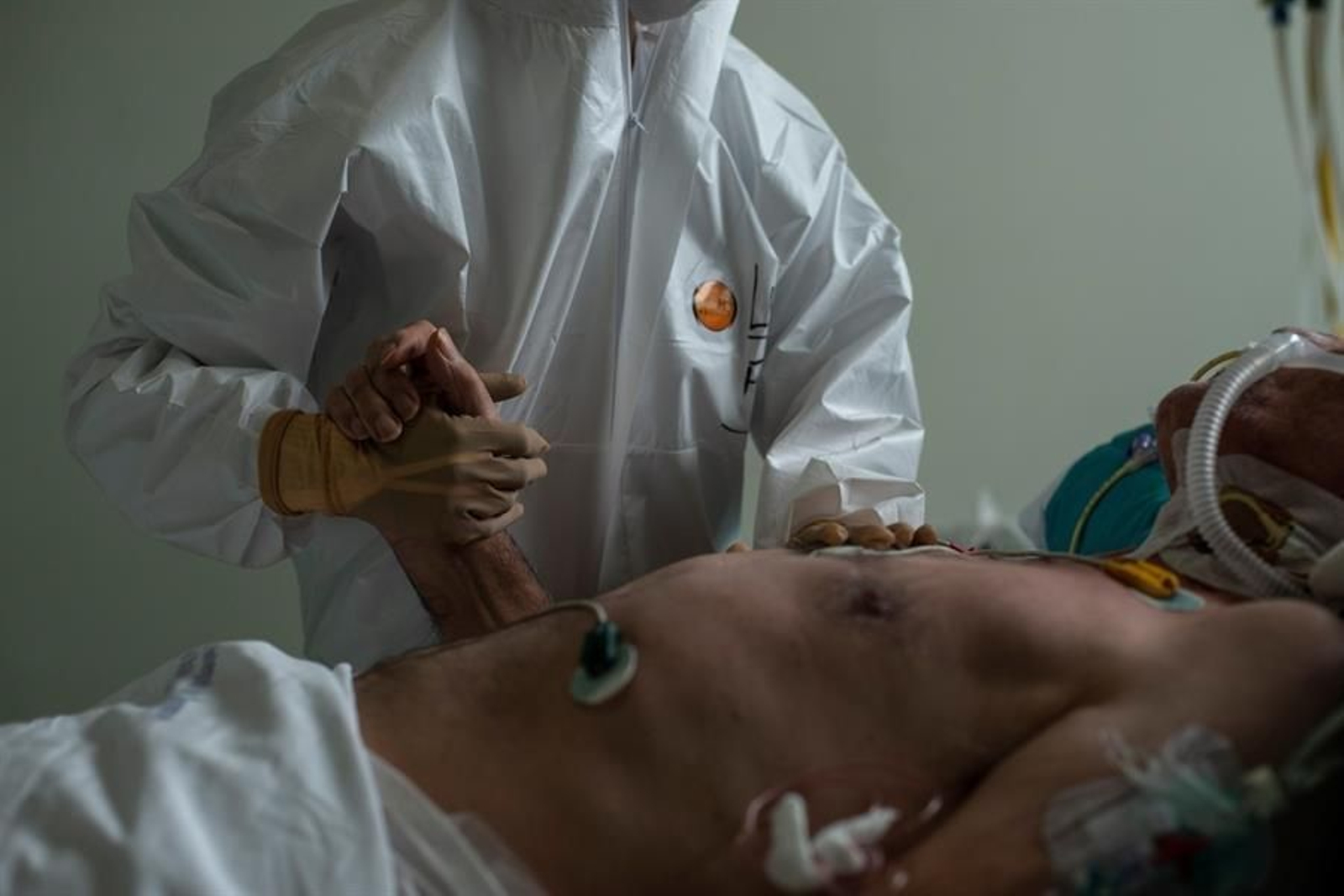 Un sanitario le da la mano a un paciente entubado en muestra de apoyo y fuerza.
EFE/ Brais Lorenzo