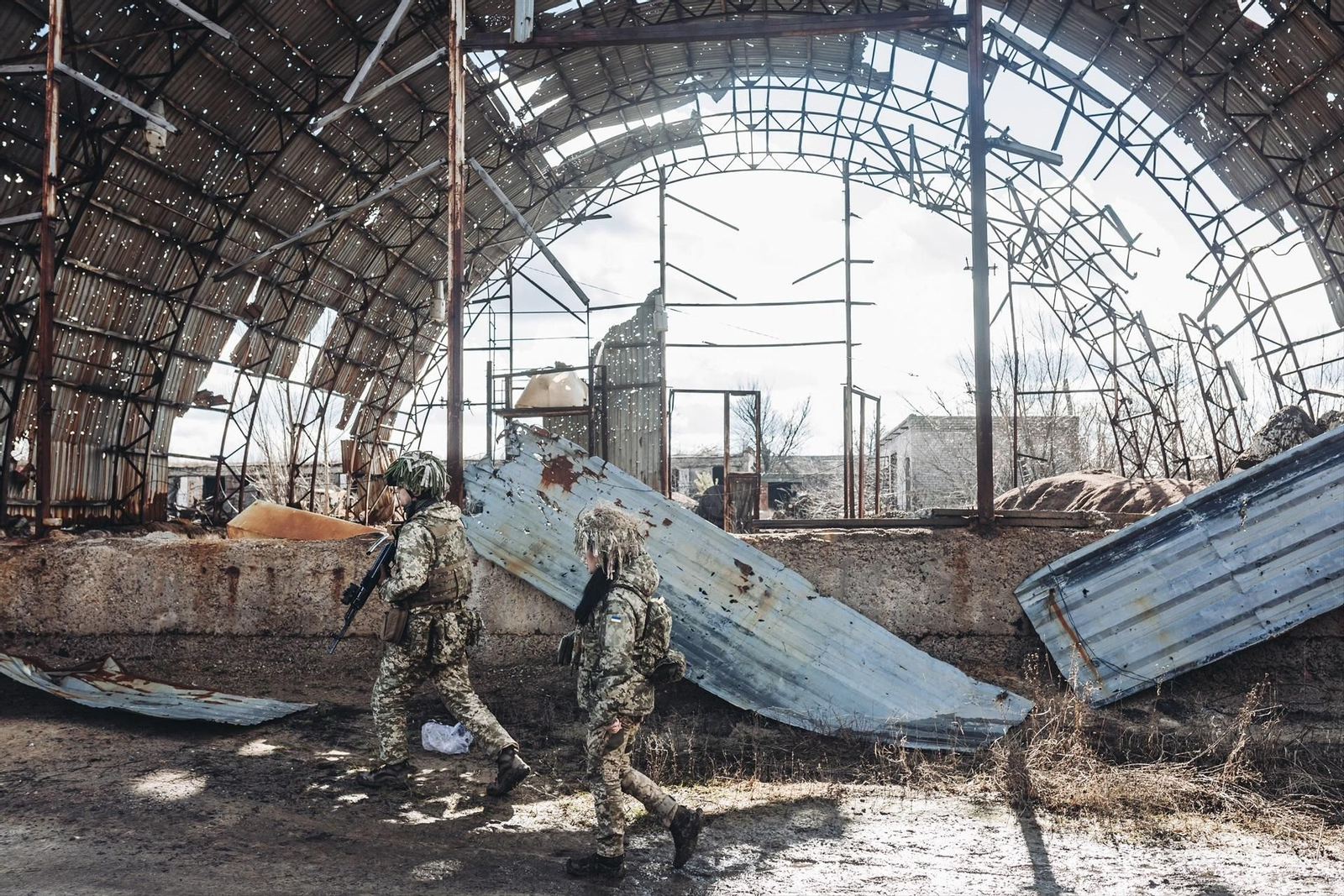 Dos soldados ucranianos frente a unas instalaciones destruidas a causa de la guerra