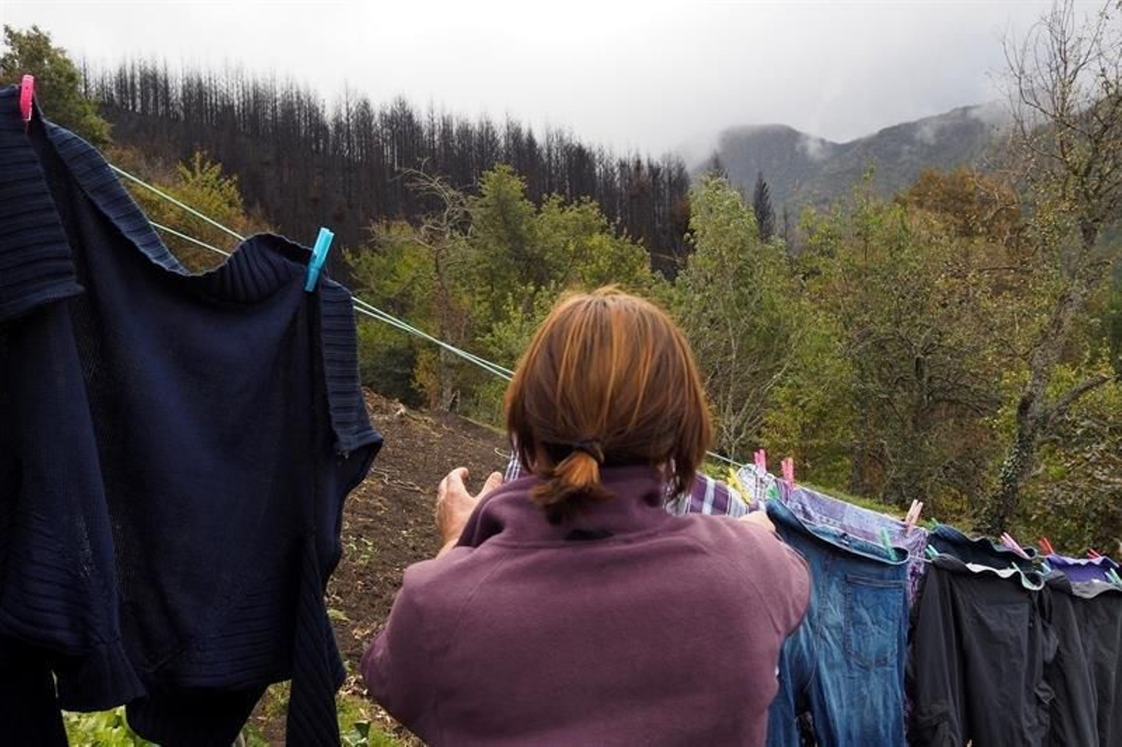 Una Vecina de Vilarello, uno de los pueblos que estuvo totalmente rodeado por el fuego, tiende la ropa en medio de un paisaje quemado, en la Reserva Natural de Los Ancares.