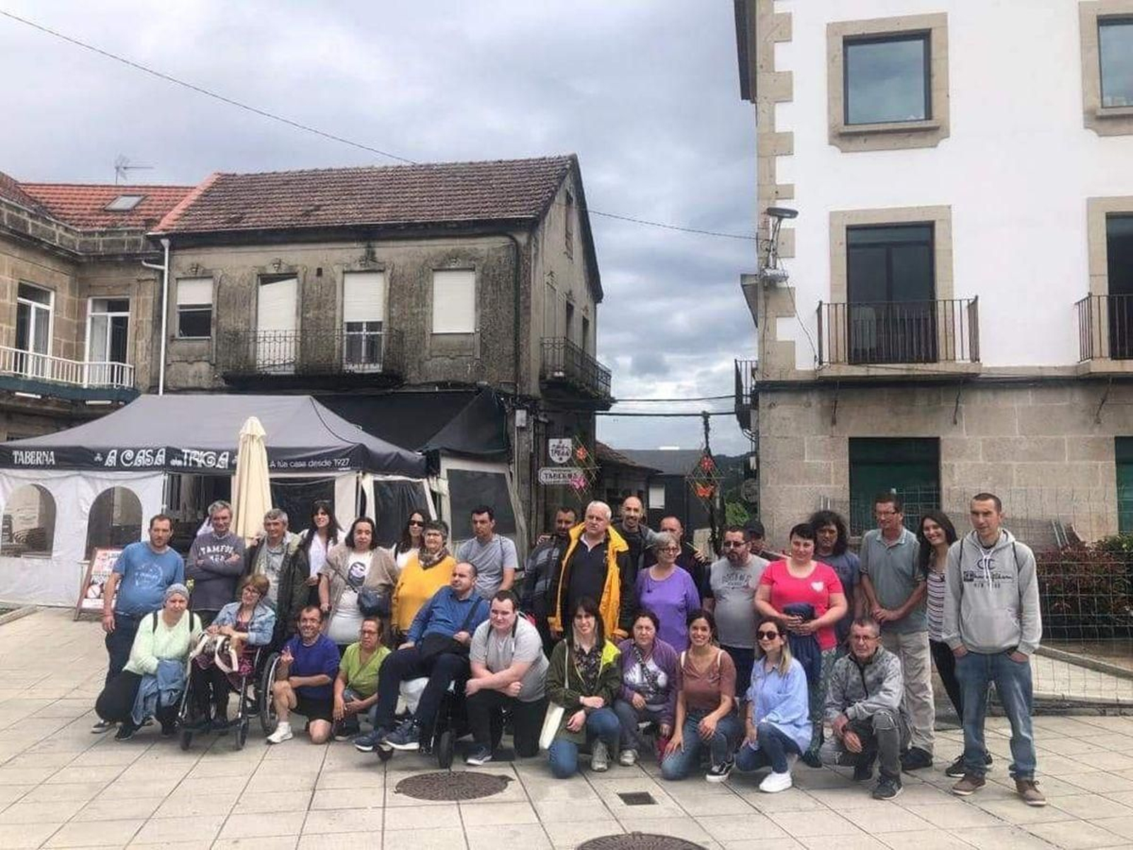 Usuarios de Avelaíña y Adapta, posaban ayer en la Praza Maior. Al fondo, sus ‘adornos de Corpus' ya colocados.