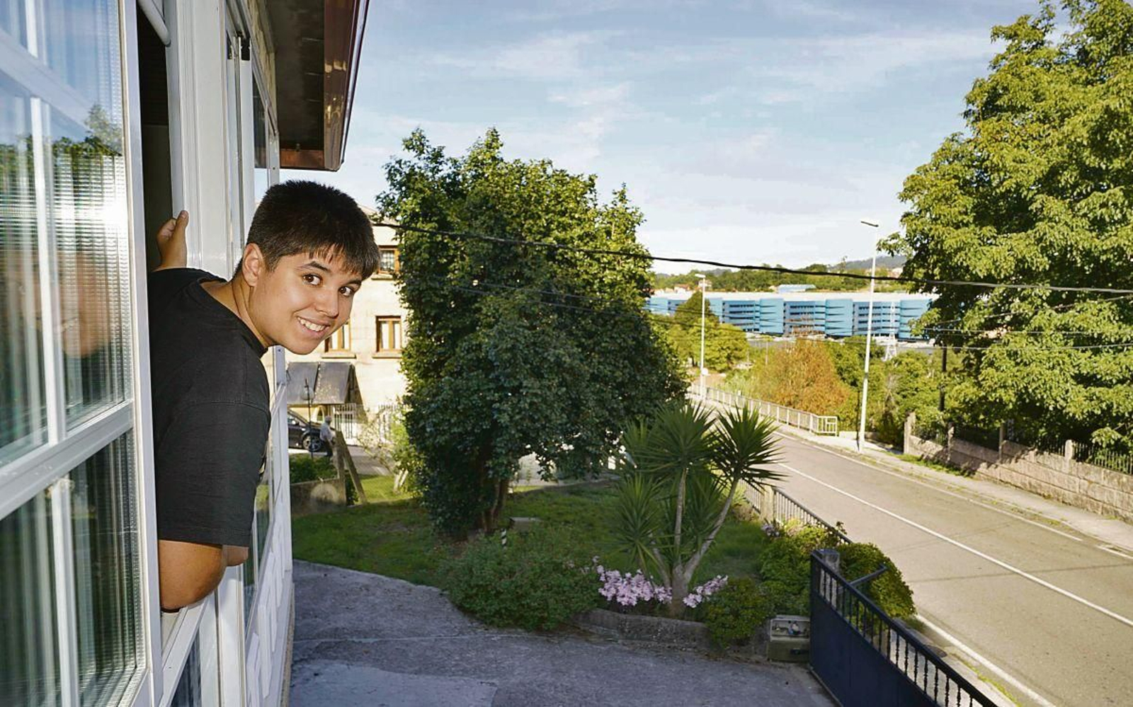 Enzo se asoma a la ventana desde su vivienda aportada por Bicos de Papel, con el Cunqueiro al fondo