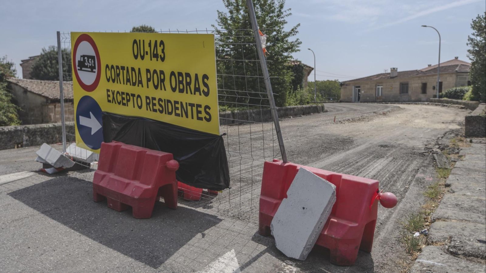 Las vallas de obras bloquean los accesos al puente, con la farmacia de fondo.